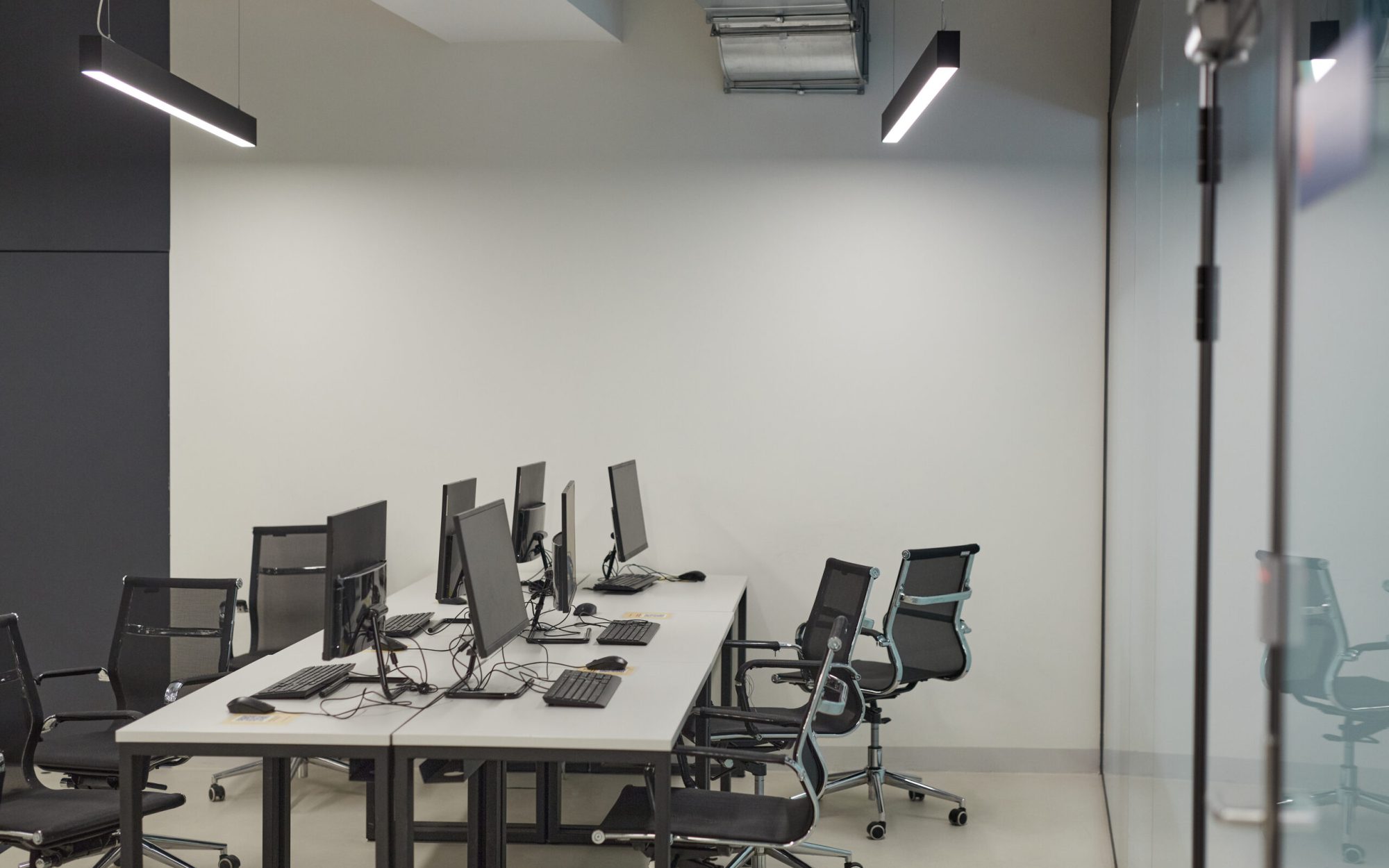 Background image of empty office with multiple computer desks and chairs, IT lab concept, copy space