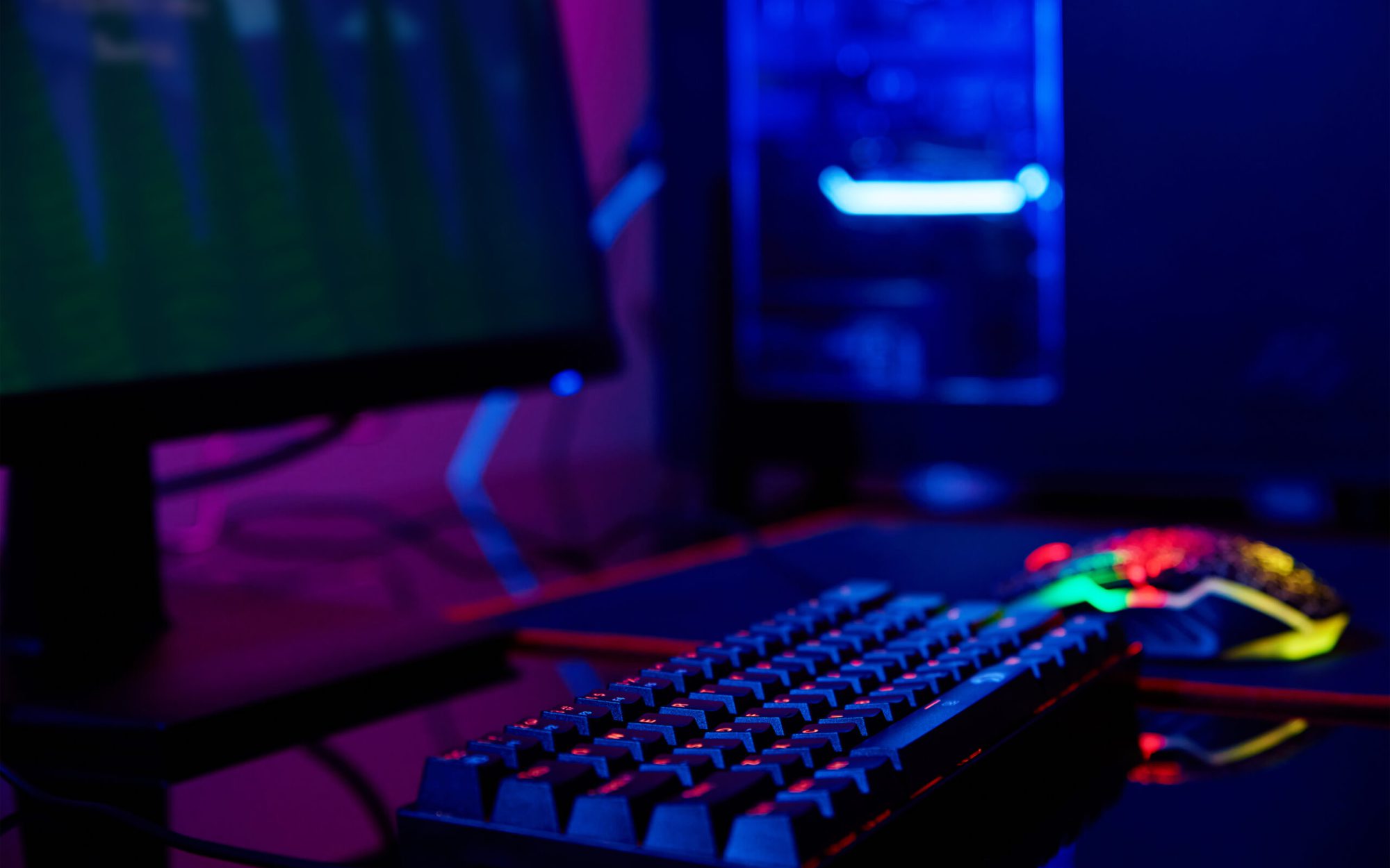 PC with rgb keyboard for gaming computer video games with neon colored background, dark room with game workplace without people